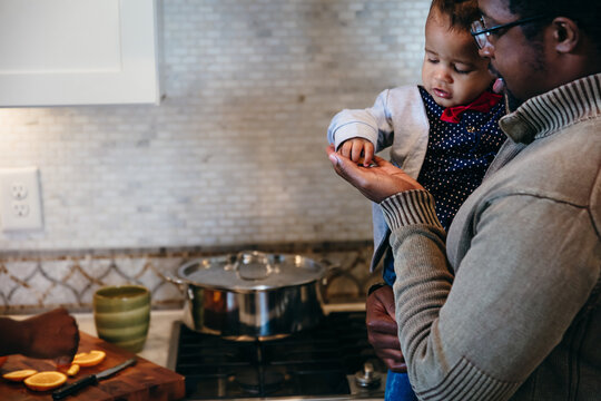 Son grabs snack from dads hand in kitchen