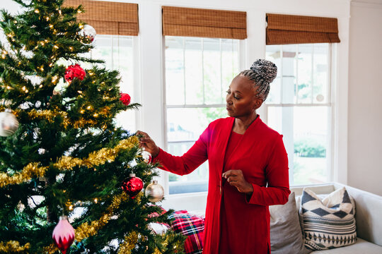 Senior Black woman decorating the Christmas tree with ornaments