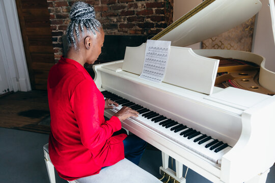 Black and white of senior Black woman with grey hair playing piano