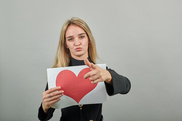 Love message on sheet, nice keeps white paper of red heart. Valentines day card. Young attractive woman, dressed black sweater with green eyes, blonde hair, background