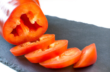 Slices of red pepper lie on a cutting board. Fresh bell pepper