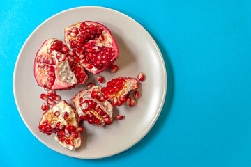 Obraz na płótnie Canvas juicy ripe pomegranate on a plate on a blue surface