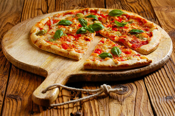 Pizza close up with rucola on wooden mat . Old wood as a background . Copy space for text or description.