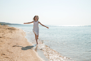 Portrait of beautiful little girl runs in sea waves.