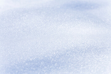 Close up macro photography texture of sparkling fresh white snow with light blue sky reflection tone. Selective focus. Winter christmas background.