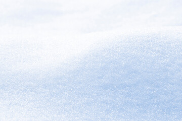Close up macro photography texture of sparkling fresh white snow with light blue sky reflection tone. Selective focus. Winter christmas background.
