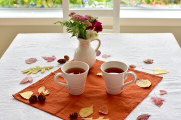 Warm fall beverage of hot tea with autumn leaves decor to sip and enjoy on cool seasonal days indoors