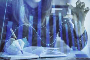 Double exposure of woman on-line shopping holding a credit card and financial graph drawing. Stock market E-commerce concept.