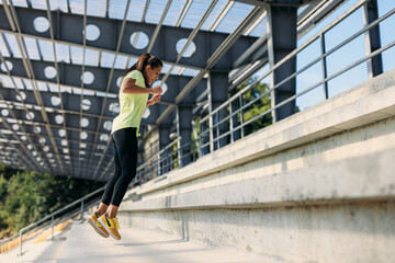 Active woman in sportswear practising in jumping on stairs