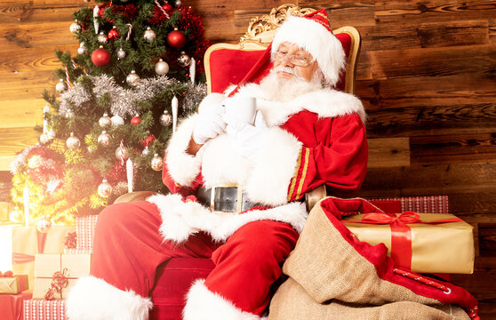 Real tired Santa Claus Sitting Near Christmas Tree