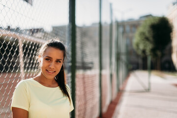 Portrait of attractive lady posing near chain fence outdoors