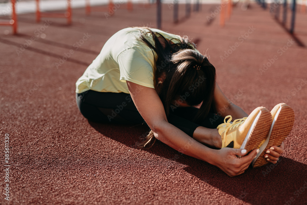 Wall mural Flexible young brunette in sport clothing stretching body