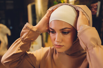 Portrait of positive pretty young Arabian woman in pink headscarf touching face with hand.