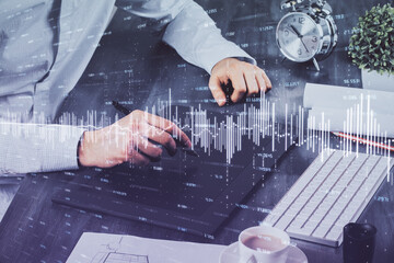 Double exposure of man's hands holding and using a phone and financial graph drawing. Analysis concept.