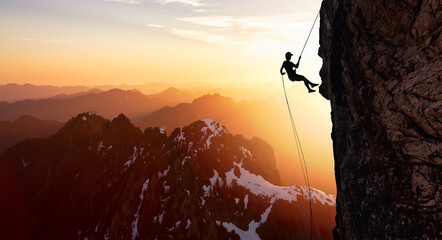 Silhouette Rappelling from Cliff. Beautiful aerial view of the mountains during a colorful and...