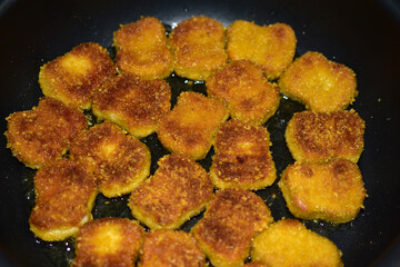 Cooking ruddy chicken nuggets in sunflower oil in a frying pan