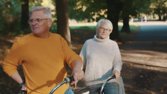 Senior couple riding double bicycle. Grandmother and grandfather cycling together . Elderly people healthy and active lifestyle. High quality 4k footage