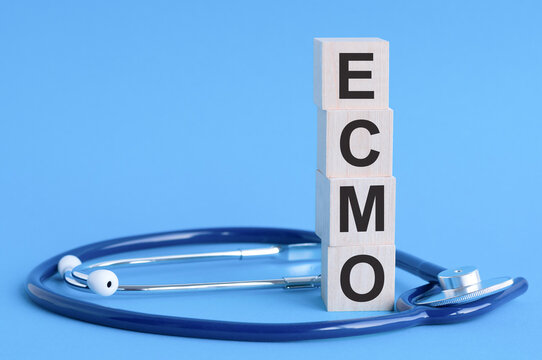 ecmo word written on wooden blocks and stethoscope on light blue background