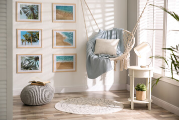 Stylish room interior with artworks and hanging chair