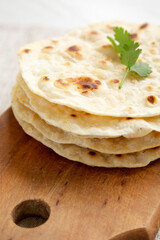 Homemade Roti Chapati Flatbread on a rustic wooden board, side view. Close-up.