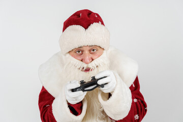 Santa Claus holds a joystick in his hands - he plays a computer game. Isolated on white