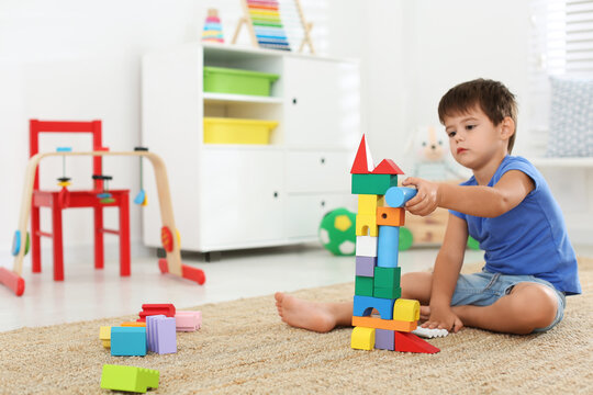 Cute Little Boy Playing With Colorful Blocks On Floor At Home. Educational Toy