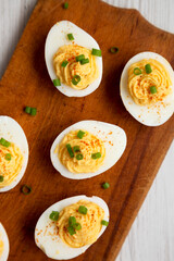Homemade Deviled Eggs with Chives on a rustic wooden board, overhead view. Flat lay, top view, from above. Close-up.
