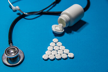 Tabletki wypadające z pudelka na niebieskim tle