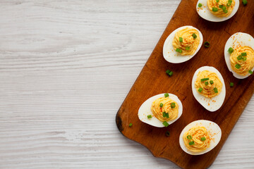 Homemade Deviled Eggs with Chives on a rustic wooden board, top view. Flat lay, overhead, from above. Space for text.