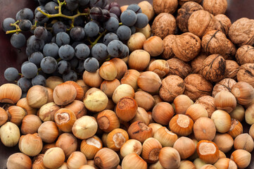 Ripe raw hazelnuts, walnuts and red grape closeup as food background
