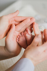 Close up of parents hands holding newborn baby's legs