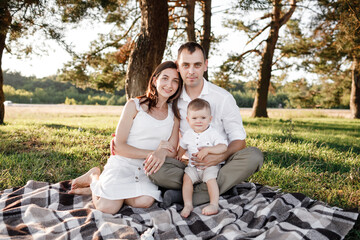 Fototapeta premium happy family mom dad and baby son happy in nature spending time together on summer sunny day. The concept of a fun holiday outdoors. Happy childhood.