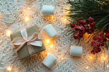 Beautiful Christmas background with present, red berries, pine branches, marshmallows and golden lights. Top view. flat lay with soft focus. Festive and holiday concept