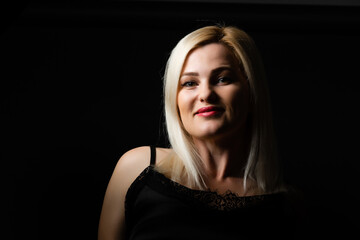 Close-up portrait of beautiful model with long blond hair on black background