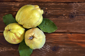 Tre mele cotogne sopra un tavolo in legno