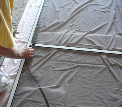 Repairing Sliding Screen Door with Spline. A homeowner is preparing to press in spline in a project to replace a damaged mesh panel in a garage sliding screen door with a metal frame.