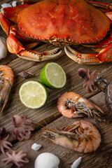 Top view of assorted seafood with lime on rustic wooden table. Concept of delicious healthy meal. Vertical format.