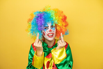 Clown standing over yellow insolated yellow background showing middle finger doing fuck you bad...
