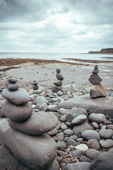 Stacked rocks into a standing still formation, pebbles by the beach put one on another as hihg as possible, groups of stones in vertical positions standing on each other