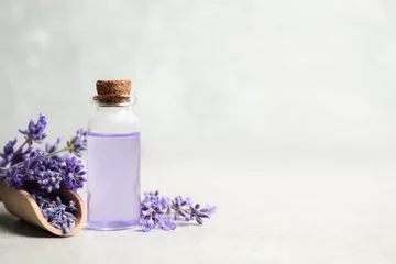 Rugzak Bottle of essential oil and lavender flowers on light stone table. Space for text © New Africa