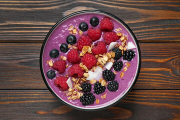 Delicious acai smoothie with berries and oatmeal on wooden table, top view