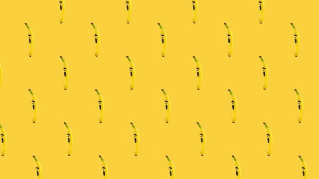 seamless looping animation pattern of bananas with painted on them scary mask of fear on a yellow background. Halloween concept for copy space