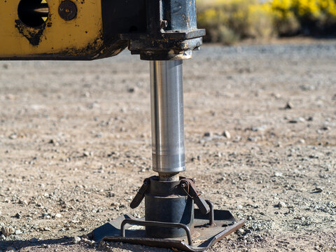 Hydraulic foot of the crane. Extended side truck outrigger stabilizer on a dirt surface.
