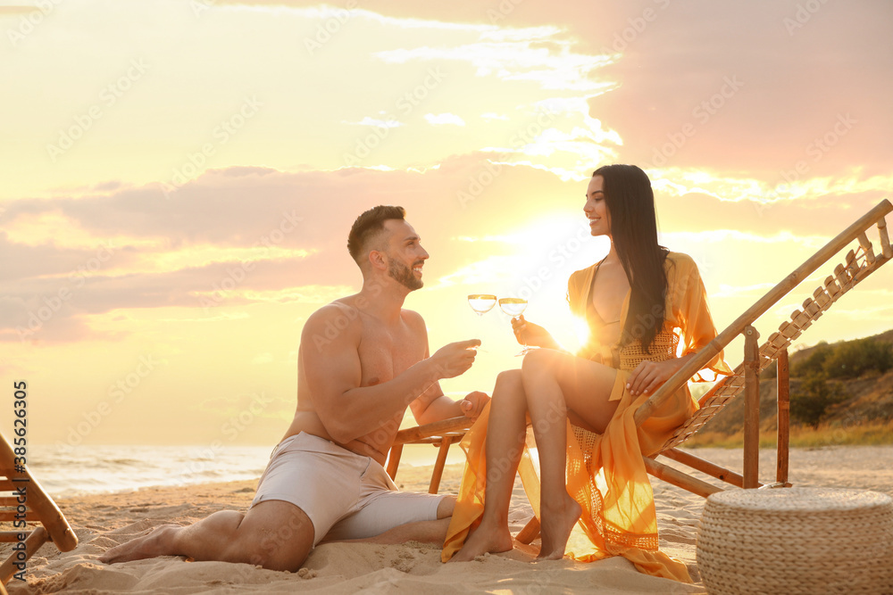 Poster Romantic couple drinking wine together on beach at sunset