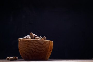 Pistachios in a wooden Cup on a dark background. Space for text