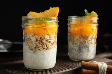 Tasty peach dessert with yogurt, chia seeds and granola on black background