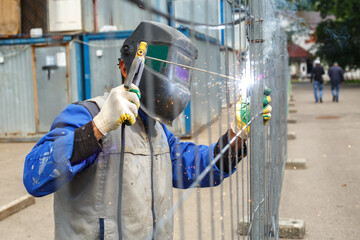 Working welder cooks metal structures. The process of welding metal products