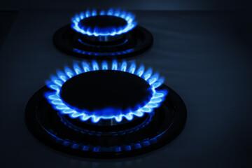 Modern gas cooktop with burning blue flames in kitchen at night