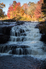 Peak fall foliage surrounds beautiful cascading lower Shohola Falls on an Autumn morning in the Pennsylvania Poconos