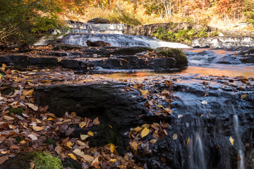 Peak fall foliage surrounds beautiful cascading upper side Shohola Falls on an Autumn morning in the Pennsylvania Poconos